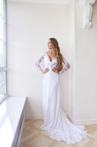 Woman standing against white wall at home