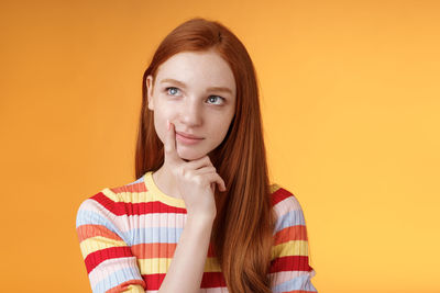 Portrait of beautiful woman against orange background