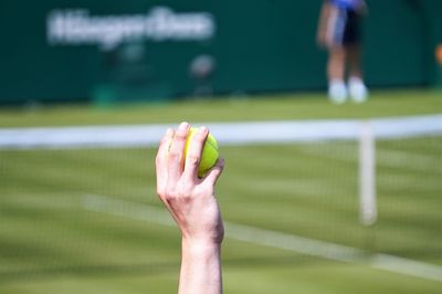 Cropped hand of tennis player throwing ball in court