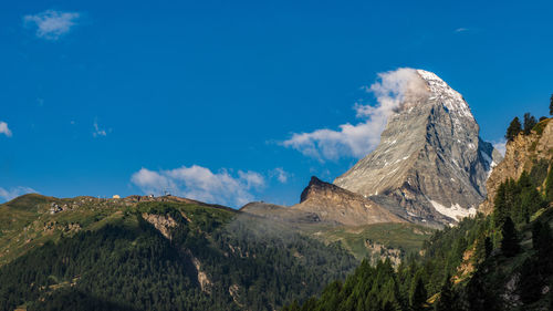 Panoramic view of snowcapped mountains against blue sky