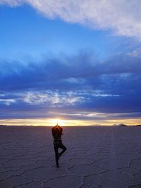 Full length of man standing on land against sky during sunset