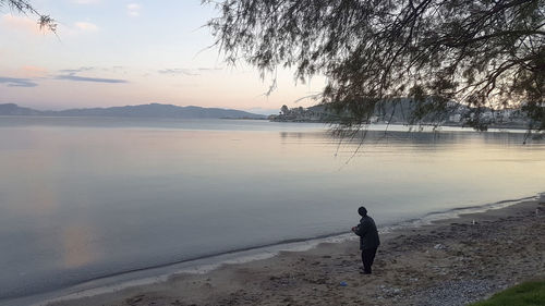 Man at beach against sky during sunset