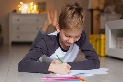 Cheerful blond hair boy enjoying drawing on the floor