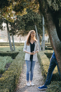 Full length of young woman standing on tree trunk