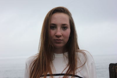 Close-up portrait of beautiful young woman against sky