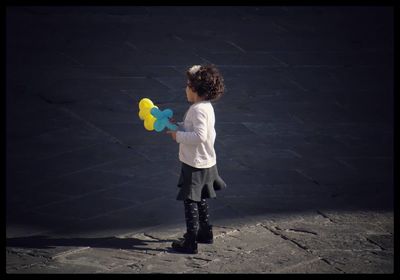 Boy playing with toy on sidewalk