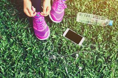 Low section of woman tying shoelace against grass at field