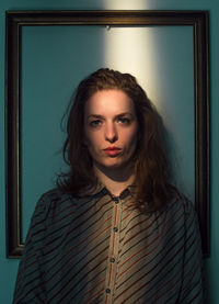 Portrait of young woman standing against wall at home