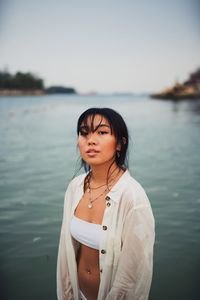 Portrait of young woman standing by sea