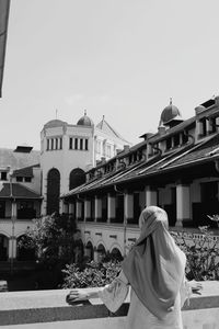 Rear view of people outside building against sky