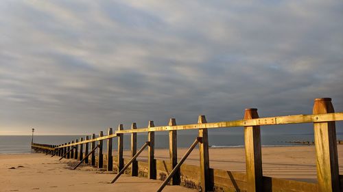 Wooden pier on sea against sky