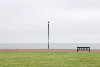 Scenic view of field by sea against sky