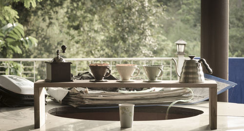 Coffee grinder with cups and teapot on table