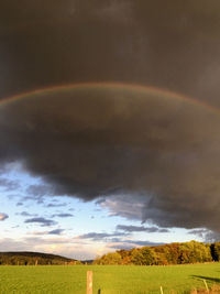 Scenic view of field against rainbow in sky