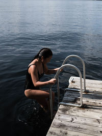 High angle view of woman in swimwear climbing ladder at lake