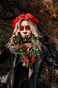 Closeup portrait of calavera catrina. young woman with sugar skull makeup and red flowers. dia de 