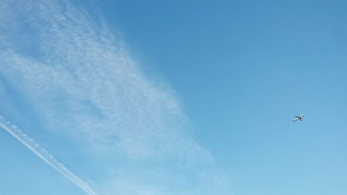 Low angle view of airplane flying against blue sky