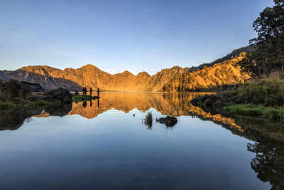 Scenic view of lake and mountains against blue sky