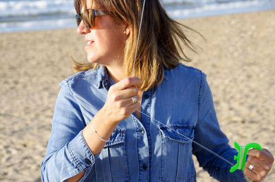 Woman looking away while flying kite at beach