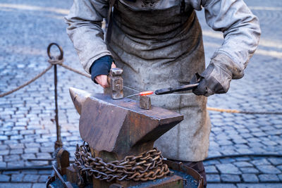 Midsection of man working on metal