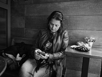 Mature woman using mobile phone while sitting on chair at home