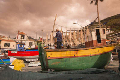 Man standing on boat moored in sea against sky