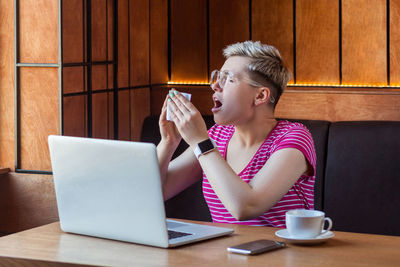 Midsection of man using mobile phone while sitting on table