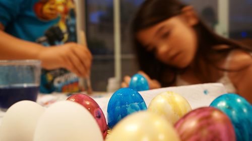 Children painting easter eggs at home