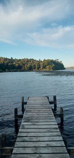 Wooden pier over lake against clear blue sky. 