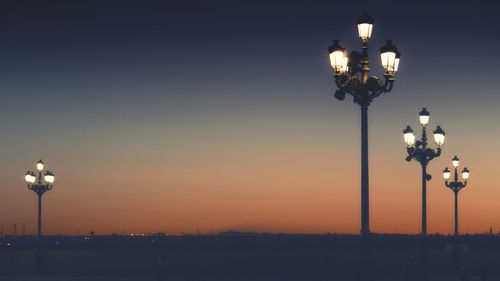 Low angle view of illuminated lights against sky during sunset