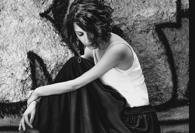 Close-up of woman sitting by wall