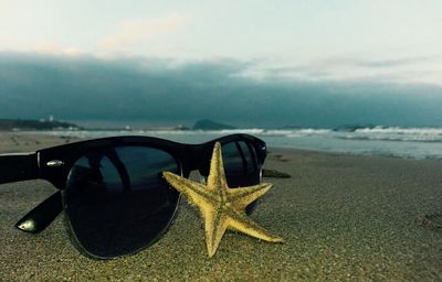 Close-up of sunglasses on beach against sky