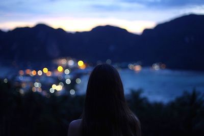 Rear view of woman against illuminated lights at night