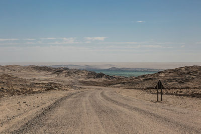 Rear view of road on desert against sky