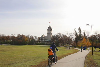 People riding bicycle on street against sky