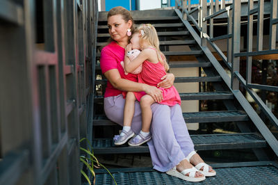 Rear view of woman sitting on railing