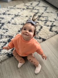 Portrait of cute baby girl sitting on wooden floor