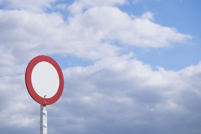 Low angle view of road sign against cloudy sky