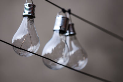Low angle view of light bulbs hanging on cable