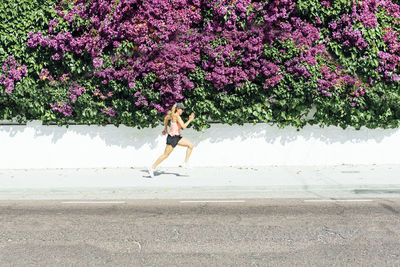 Woman jogging on street , with colorful flowers background