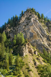 Low angle view of rocky mountain against blue sky