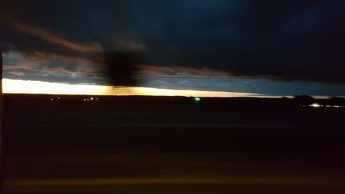 Scenic view of lake against cloudy sky at sunset