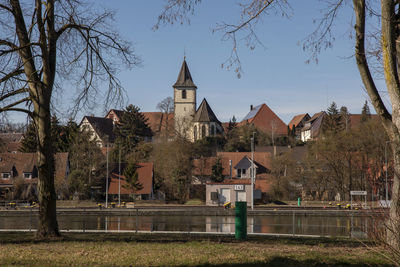 Houses by trees and buildings against sky