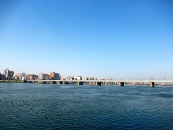 Sea by buildings against clear blue sky