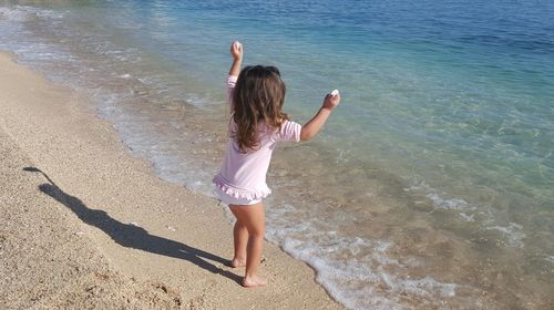 Rear view of girl standing at beach