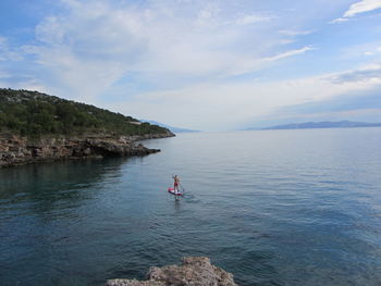 Man paddleboarding in sea against sky