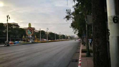 Road by trees against sky in city