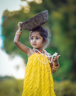 Girl holding wicker basket on head looking away outdoors