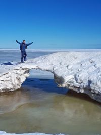 Man standing in sea against clear blue sky