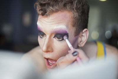 Young man applying drag makeup